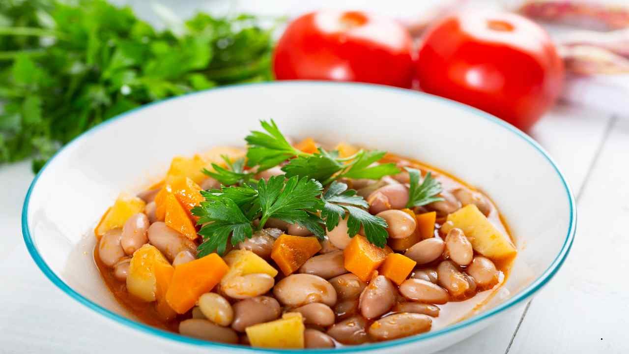Bowl of seasoned pinto beans with carrots, parsley, and tomatoes served fresh with rich broth