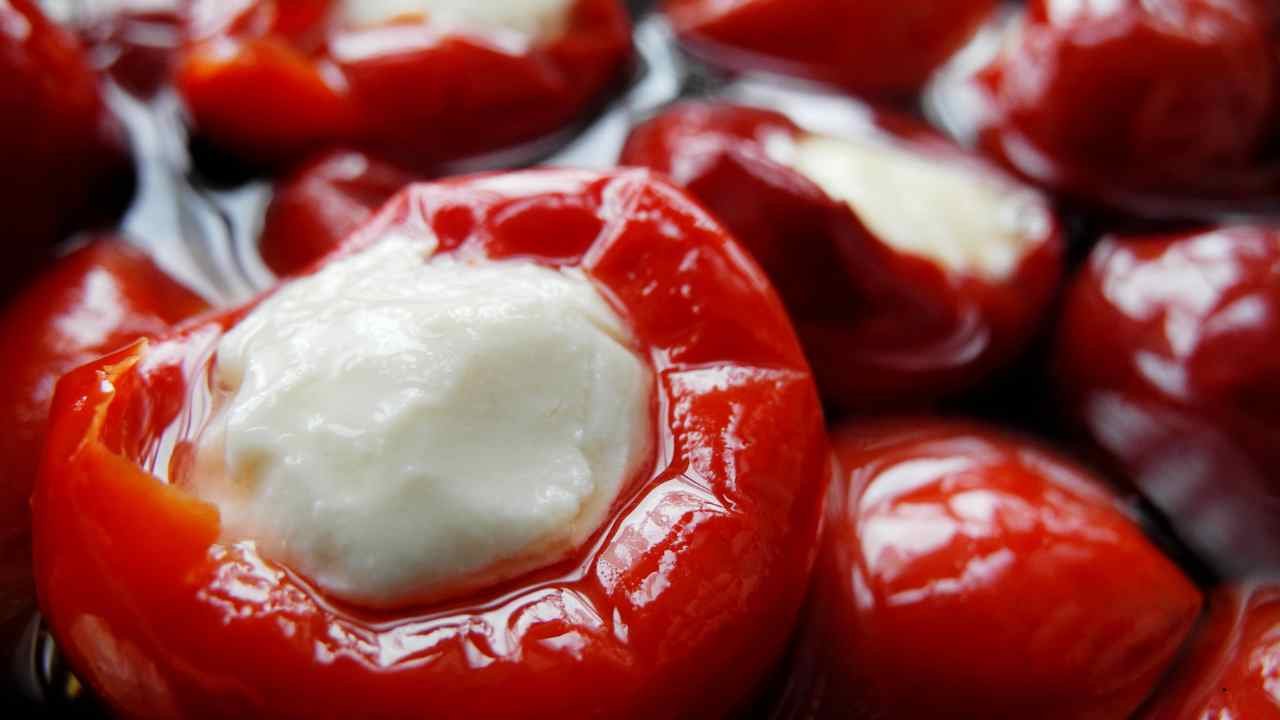 Close-up of juicy red cherry peppers stuffed with creamy cheese in olive oil