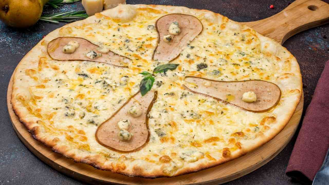 Pear and Gorgonzola pizza topped with sliced pears and melted cheese on a wooden board